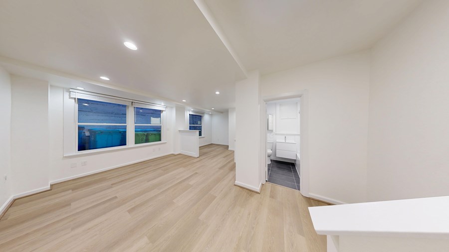 A spacious room with wooden floors and white walls.